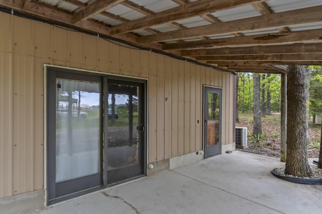 view of exterior entry featuring cooling unit and a patio