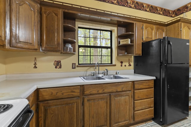 kitchen with open shelves, a sink, freestanding refrigerator, and light countertops