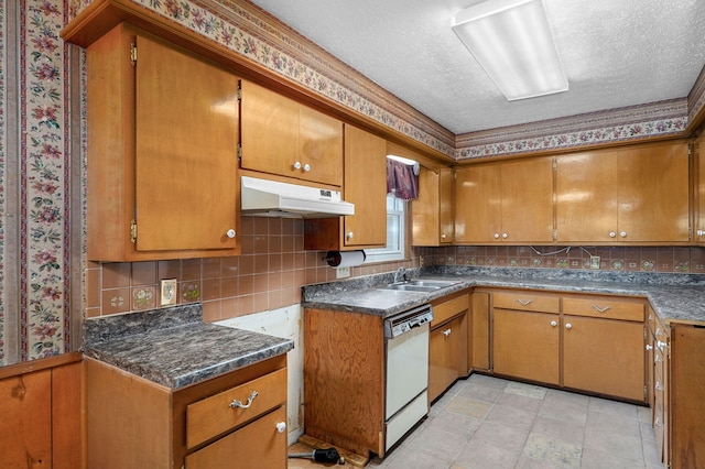 kitchen featuring a sink, white dishwasher, brown cabinetry, a textured ceiling, and under cabinet range hood