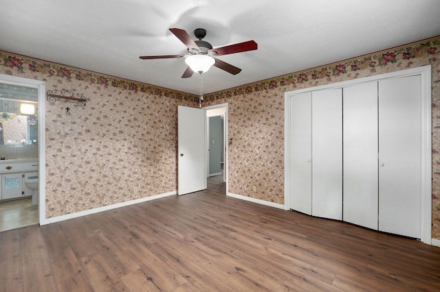 unfurnished bedroom with hardwood / wood-style flooring, baseboards, and wallpapered walls