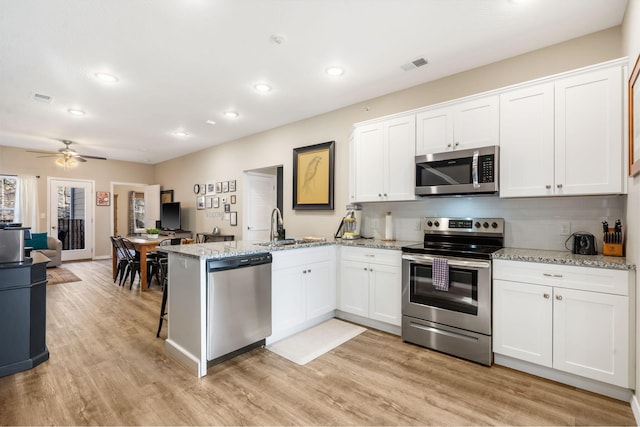 3112 S Vinyards Terrace Parkway Unit 4, Branson, MO 65616 - kitchen with appliances with stainless steel finishes, a sink, a peninsula, white cabinetry, and light wood-type flooring
