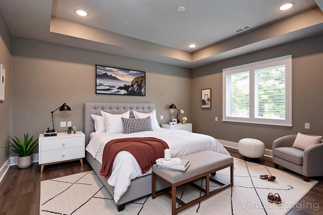 bedroom featuring a raised ceiling, baseboards, wood finished floors, and recessed lighting