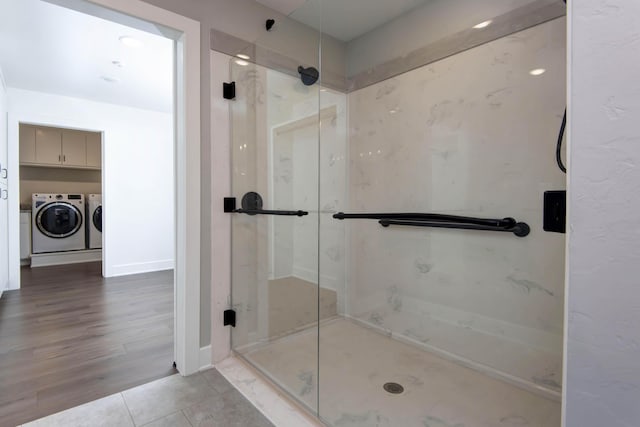 full bath featuring a marble finish shower, independent washer and dryer, and tile patterned flooring