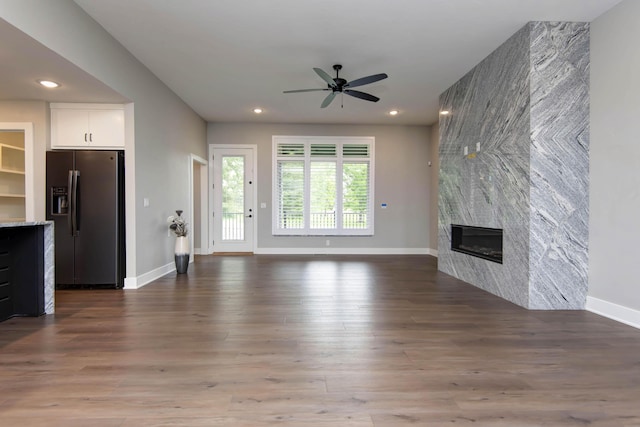 unfurnished living room with a ceiling fan, a tiled fireplace, baseboards, recessed lighting, and wood finished floors