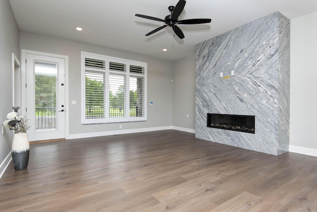unfurnished living room with baseboards, plenty of natural light, a large fireplace, a ceiling fan, and recessed lighting