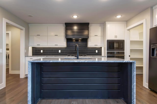 kitchen featuring a sink, black appliances, custom range hood, dark wood-style flooring, and white cabinets