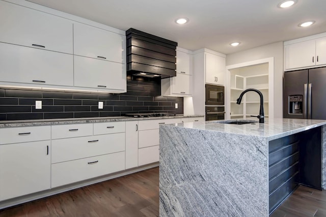 kitchen featuring a sink, dark wood finished floors, black appliances, backsplash, and light stone counters