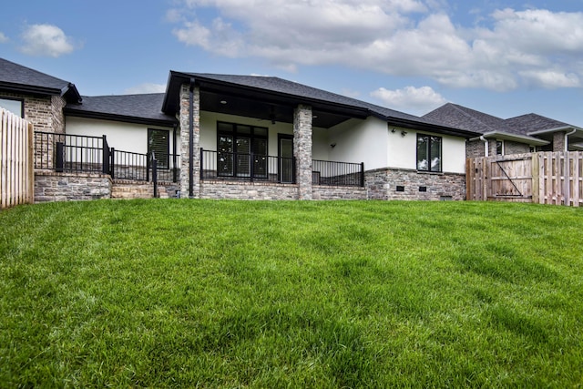 rear view of property with stucco siding, roof with shingles, and stone siding