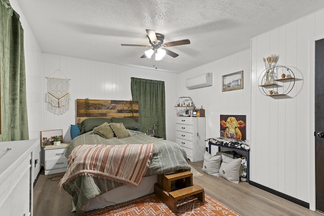 311 S Center St, Fordland, MO 65652 - bedroom with a wall mounted air conditioner, light wood-style floors, ceiling fan, a textured ceiling, and a decorative wall
