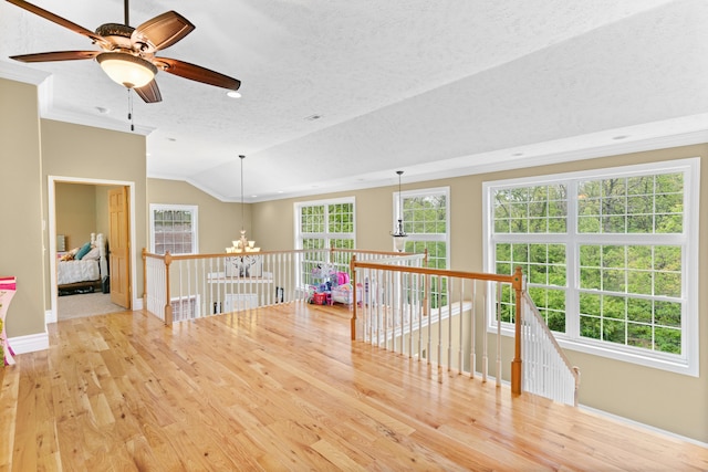 empty room with a textured ceiling, baseboards, wood finished floors, lofted ceiling, and a chandelier