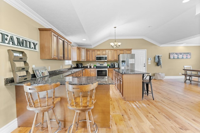 kitchen with stainless steel appliances, a kitchen breakfast bar, baseboards, vaulted ceiling, and light wood-style flooring