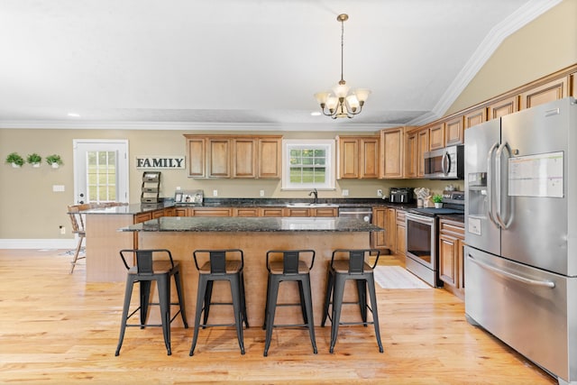 kitchen featuring appliances with stainless steel finishes, a sink, ornamental molding, a kitchen bar, and a chandelier
