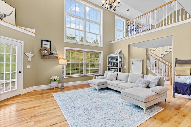 living room featuring a high ceiling, wood finished floors, a chandelier, stairway, and plenty of natural light
