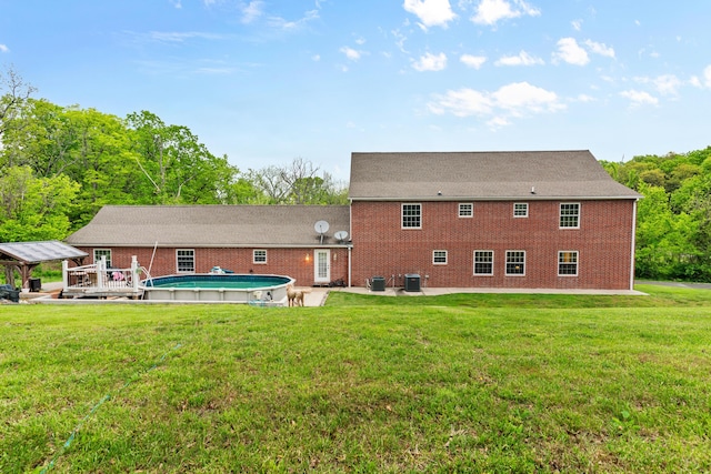 back of property featuring a patio area, a yard, an outdoor pool, and central AC unit