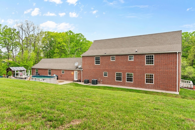 rear view of house with a patio area, central air condition unit, brick siding, and a yard