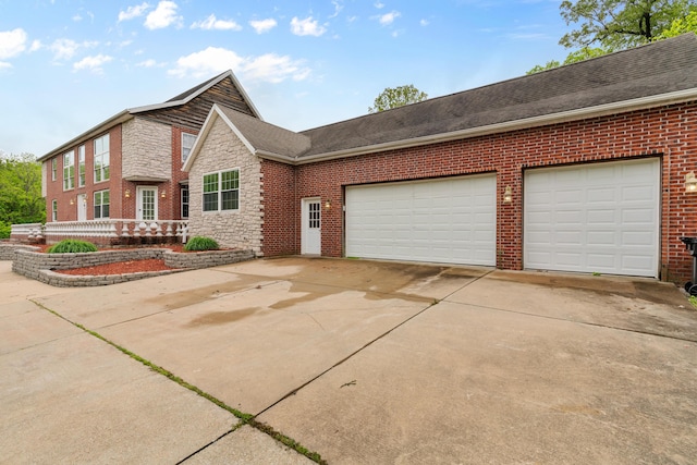 view of front of home with concrete driveway, brick siding, a garage, stone siding, and a shingled roof