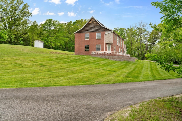 back of house featuring a storage shed, an outdoor structure, a yard, and brick siding