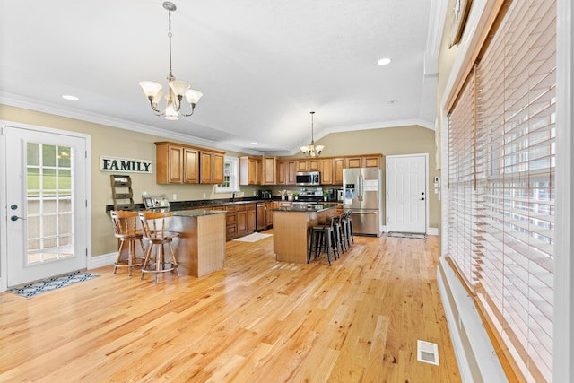 kitchen with stainless steel appliances, a chandelier, a kitchen breakfast bar, a sink, and ornamental molding