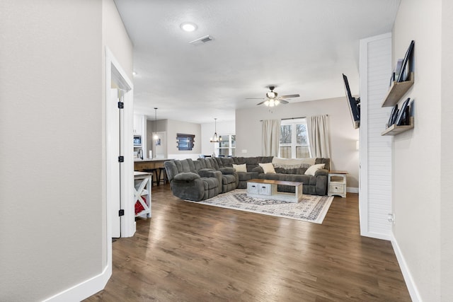 living area featuring ceiling fan, dark wood-style floors, and baseboards