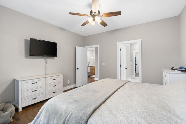 bedroom with dark wood-type flooring, a sink, baseboards, ceiling fan, and ensuite bathroom