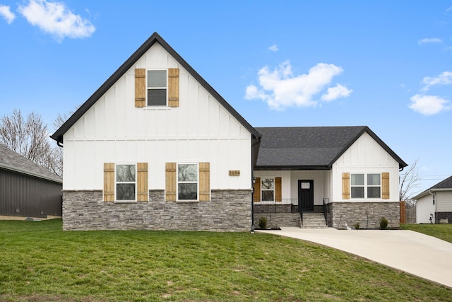 view of front facade featuring board and batten siding, stone siding, a front yard, and a shingled roof