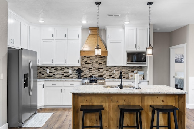 kitchen with stainless steel appliances, custom range hood, wood finished floors, and white cabinetry