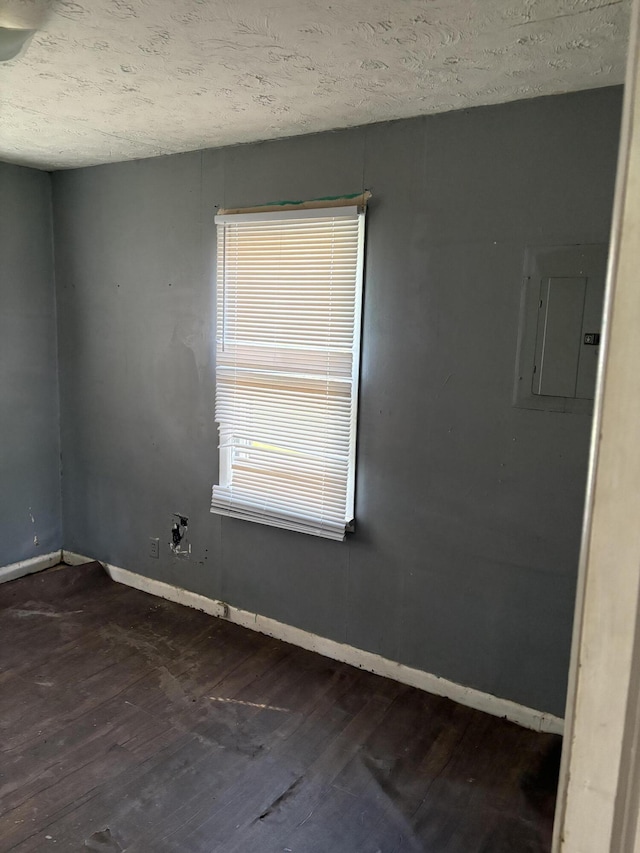 unfurnished room with dark wood-style floors, electric panel, baseboards, and a textured ceiling