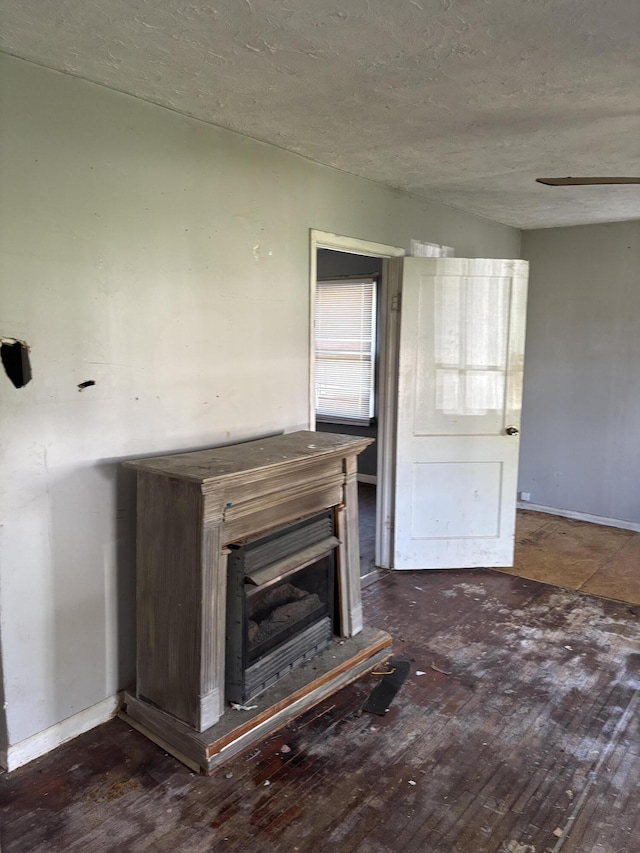unfurnished living room featuring hardwood / wood-style flooring, baseboards, and a textured ceiling