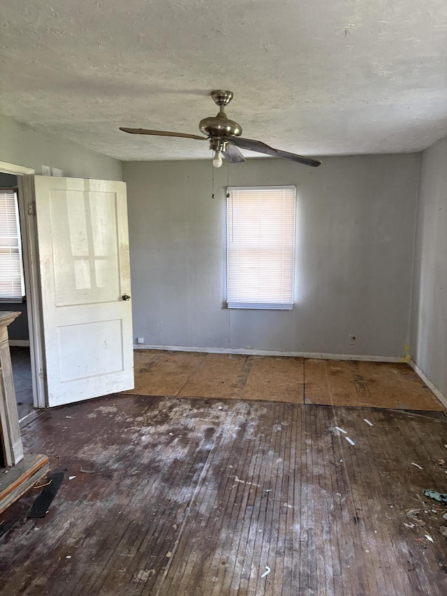 spare room with wood-type flooring, a ceiling fan, baseboards, and a textured ceiling