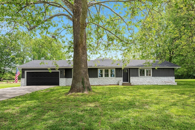 ranch-style home with stone siding, an attached garage, concrete driveway, and a front lawn