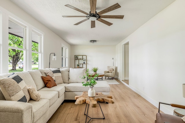 living room with a ceiling fan, light wood finished floors, and baseboards