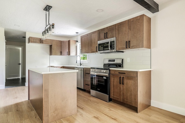kitchen with appliances with stainless steel finishes, tasteful backsplash, light wood-style flooring, and hanging light fixtures