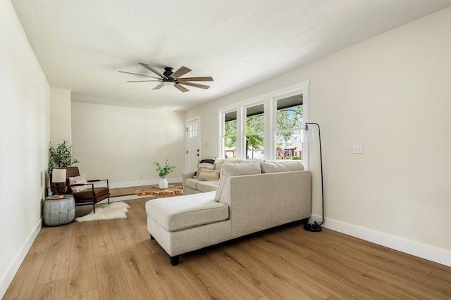 living room featuring a ceiling fan, light wood-type flooring, and baseboards