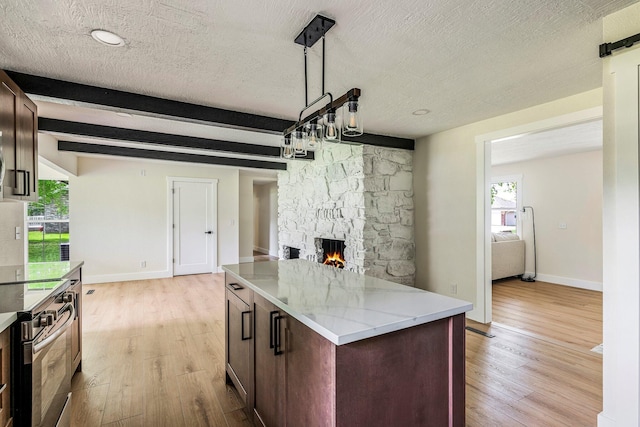 kitchen with stainless steel range with electric stovetop, a textured ceiling, a stone fireplace, light wood-style flooring, and beamed ceiling