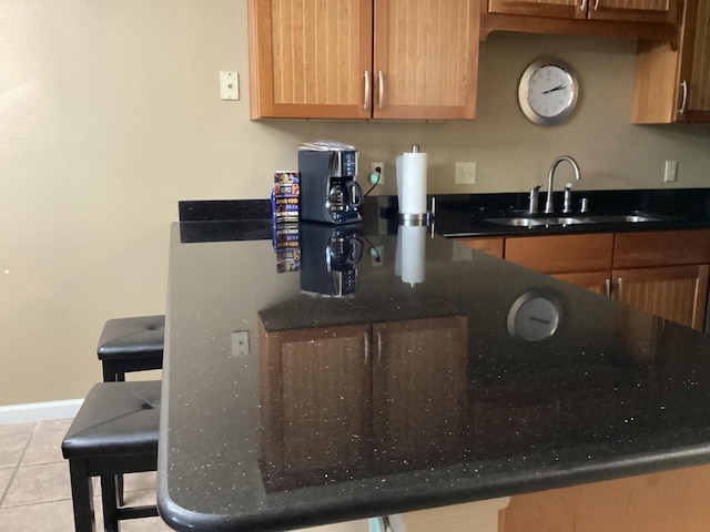 186 Bunker Ridge Dr Unit 2, Branson, MO 65616 - kitchen featuring a sink, light tile patterned floors, baseboards, and dark stone countertops