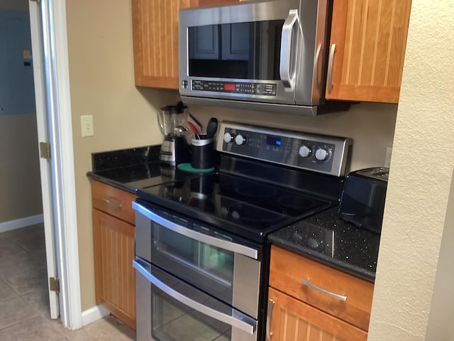 186 Bunker Ridge Dr Unit 2, Branson, MO 65616 - kitchen with appliances with stainless steel finishes, light tile patterned flooring, dark stone counters, and baseboards