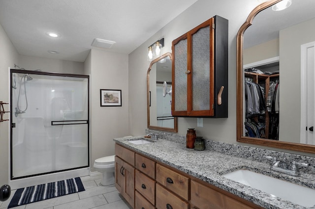full bath with a shower stall, toilet, double vanity, a spacious closet, and tile patterned flooring