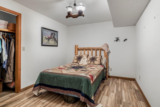 4949 S 196th Rd, Halfway, MO 65663 - bedroom featuring a chandelier, light wood-type flooring, a textured ceiling, and baseboards