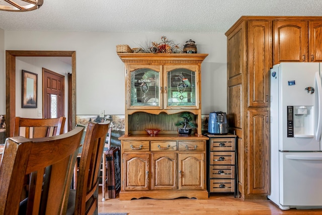 4949 S 196th Rd, Halfway, MO 65663 - kitchen featuring white fridge with ice dispenser, a textured ceiling, brown cabinetry, and light wood finished floors