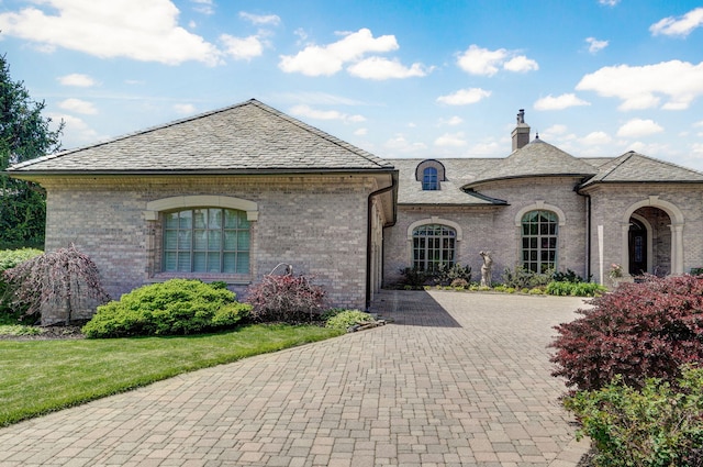 5245 S Stonehaven Dr, Springfield, MO 65809 - french country inspired facade with decorative driveway, a chimney, brick siding, a high end roof, and a front lawn