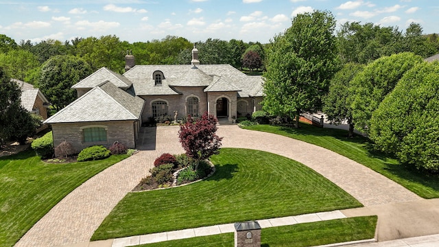 5245 S Stonehaven Dr, Springfield, MO 65809 - french country home with curved driveway, a front lawn, a chimney, and stone siding