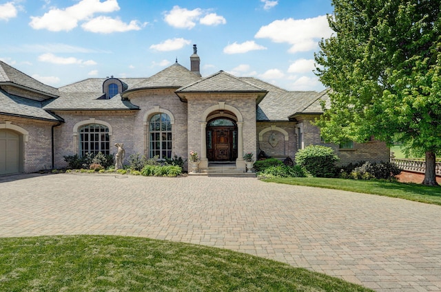 5245 S Stonehaven Dr, Springfield, MO 65809 - french country home featuring a chimney, a high end roof, brick siding, and driveway
