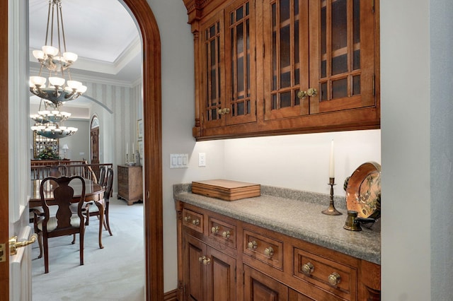 5245 S Stonehaven Dr, Springfield, MO 65809 - bar featuring arched walkways, ornamental molding, a chandelier, light colored carpet, and hanging light fixtures