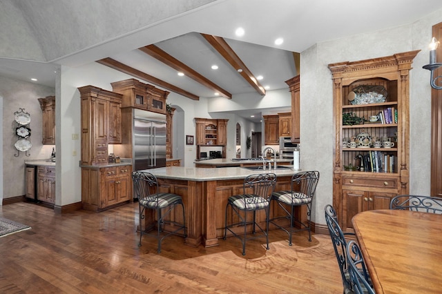 5245 S Stonehaven Dr, Springfield, MO 65809 - kitchen with a kitchen bar, brown cabinets, wood finished floors, a peninsula, and beamed ceiling