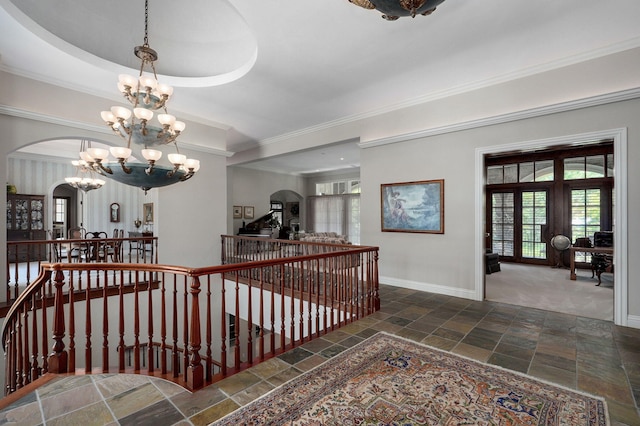 5245 S Stonehaven Dr, Springfield, MO 65809 - hall featuring an upstairs landing, stone tile flooring, arched walkways, a chandelier, and baseboards
