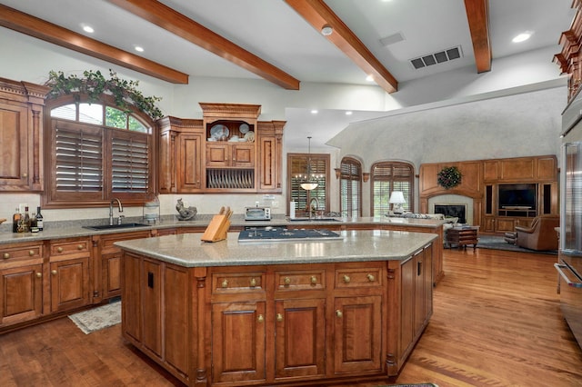 5245 S Stonehaven Dr, Springfield, MO 65809 - kitchen featuring a sink, stainless steel gas cooktop, beamed ceiling, brown cabinetry, and a kitchen island