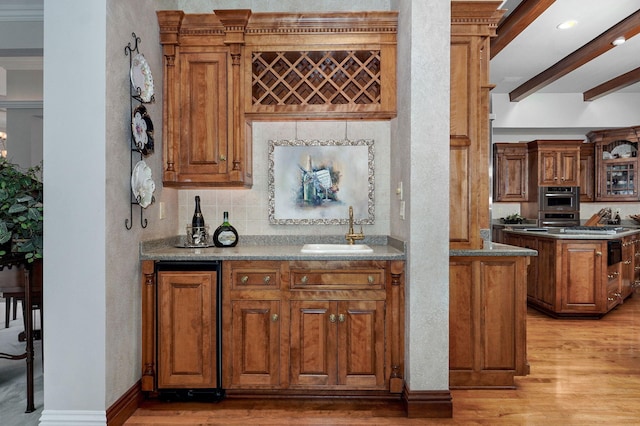 5245 S Stonehaven Dr, Springfield, MO 65809 - indoor wet bar featuring light wood-style floors, tasteful backsplash, beam ceiling, baseboards, and stainless steel double oven