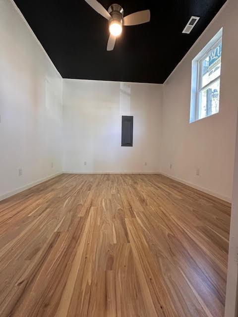 spare room featuring light wood-style flooring, a ceiling fan, and baseboards