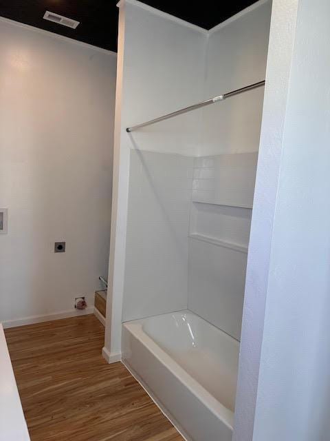full bathroom featuring wood finished floors, baseboards, and bathing tub / shower combination