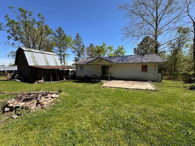 back of house featuring an outdoor fire pit, a patio, and a yard